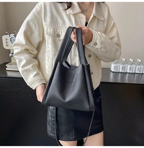 Close-up of black lychee grain leather tote bag with FASHION embossed detail and dual straps