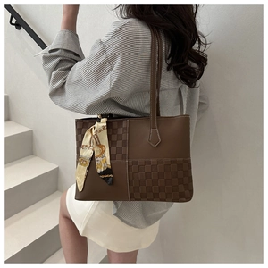 Detail view of large brown plaid tote bag with silk scarf on a minimalist staircase