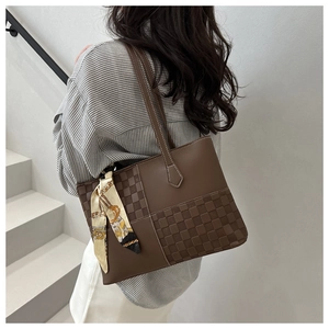 Brown leather tote bag with woven texture and silk scarf shown on model shoulder