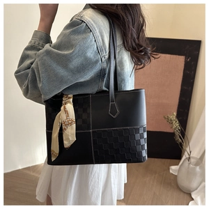 Detail of black tote bag featuring plaid texture patchwork and silk scarf handles decoration