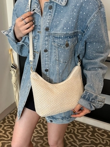 Large beige woven straw shoulder bag with half-moon shape for a casual bohemian style