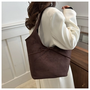 Detail of dark brown matte suede shoulder bag with elegant bow tie decoration on model