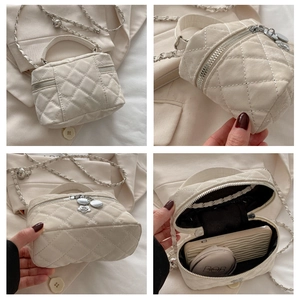 Detail view of cream quilted bucket bag showing chain strap and spacious interior storage