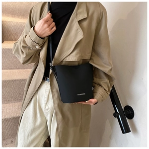 Schicke schwarze matte Beuteltasche mit Fashion-Bags-Text an einem Modell in Alltagsszene
