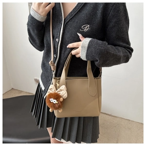 Detail of khaki leather bucket bag with plush monster charm and adjustable strap