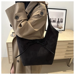Détail du sac sous le bras en daim noir avec nœud sur un trench-coat kaki
