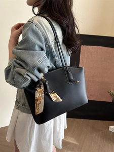 Minimalist black tote bag with printed silk scarf and metal hardware in side-view carry