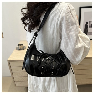 Close-up of black half-moon shoulder bag with lace-up detail and metal eyelets