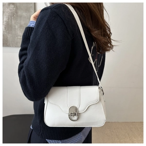 Detail of white leather shoulder bag featuring a silver oval metal clasp and curved flap