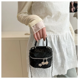 Detail of black velvet quilted mini bag with silver camellia charms and chain strap