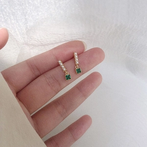 Hand holding elegant 925 silver earrings with emerald zircon and pearl accents