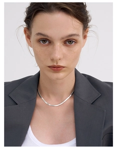 Macro detail of S925 sterling silver flat snake chain necklace with mirror finish on model