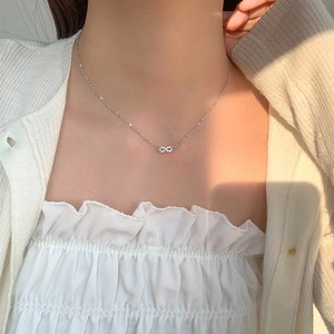 Close-up of S925 silver infinity pendant necklace with micro-set zircons on woman