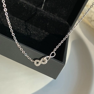 Macro shot of silver infinity pendant necklace with cubic zirconia on black velvet