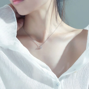 Detail of s925 silver geometric circle necklace worn on a textured white blouse