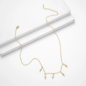 Elegant gold S925 silver lightning pendant necklace with zircons shown on white blocks