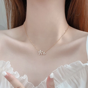 Detail of elegant gold necklace featuring double cherry blossom petals on a model's collarbone