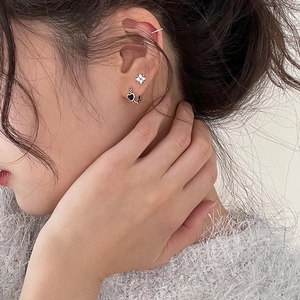 Macro close-up of S925 silver vintage black heart earrings and star stud on model ear