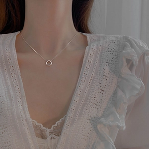 Macro view of a 925 silver star circle necklace worn on neck with white lace top