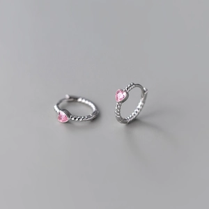 Macro detail of heart-shaped pink zircon earrings with twisted rope metal design