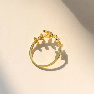 Macro detail of gold-plated leaf ring featuring micro-paved zircons and leaf shadows
