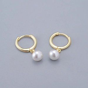 Detail of elegant gold huggie hoop earrings with polished white pearl pendants