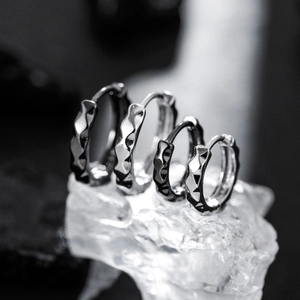Irregular geometric textured silver ear cuffs set on ice blocks with a dark background