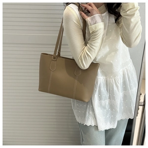 Detail view of khaki tote bag featuring contrast white stitching and premium faux leather texture