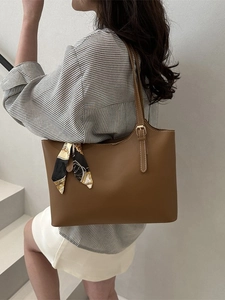 Brown leather tote bag with vintage printed scarf on model in modern urban setting