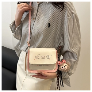 Detail of cartoon printed beige crossbody bag with teddy bear charm on adjustable strap