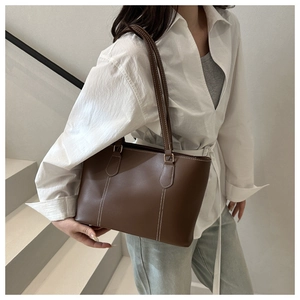 Close-up of deep brown leather tote bag with white contrast stitching and dual handles