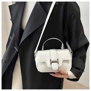Detail of white patent leather handbag with silver metallic buckle and glossy finish