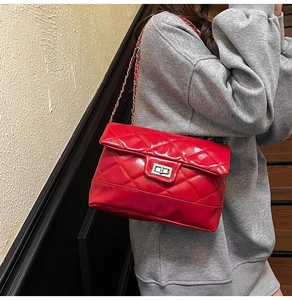 Détail du sac matelassé rouge en cuir verni avec fermoir rotatif métallique argenté