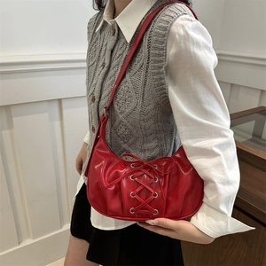 Red patent leather crescent bag with decorative bow and ribbon lace-up design