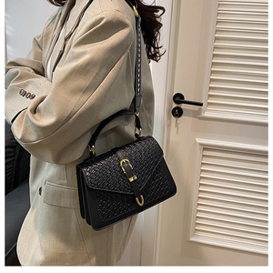 Detail of black woven leather handbag with gold buckle and geometric fabric strap