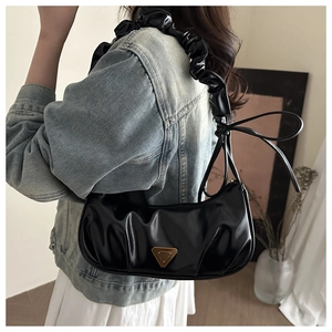 Detail der schwarzen Falten-Schultertasche mit Knotengriff und dreieckigem Metallemblem