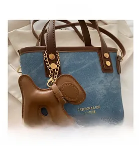 Detail of blue denim mini tote bag with brown leather handles and a cute puppy charm