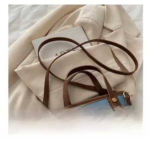 Detail showing the denim fabric with brown leather trim and golden metal rivet accents