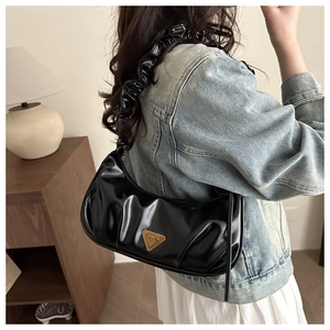 Detail der schwarzen glänzenden Handtasche mit Falten-Design und gerafftem Schultergurt