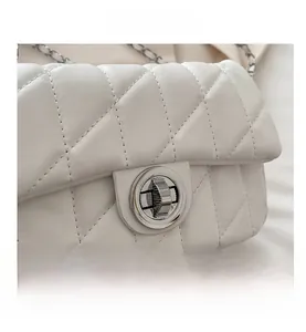 Detailed macro view of white diamond quilted leather bag with silver metal turn-lock