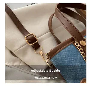 Detailed close-up of adjustable strap buckle and leather stitching on denim bucket bag