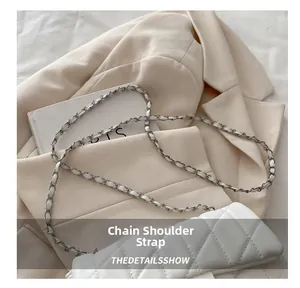 Detail of white quilted crossbody bag featuring metal and leather patchwork chain strap