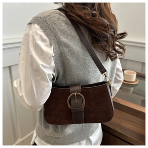 Detail der dunkelbraunen Wildleder-Umhängetasche mit Bronzeschnalle im Lifestyle-Stil