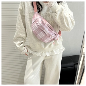 Detail of pink plaid corduroy saddle bag with adjustable strap and charm on a model