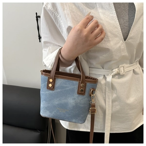 Detail der hellblauen Canvas-Beuteltasche mit braunem Lederbesatz und Goldlogo
