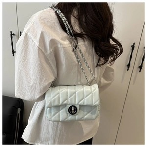 Chic quilted chain bag in light blue leather finish worn as a crossbody shoulder bag