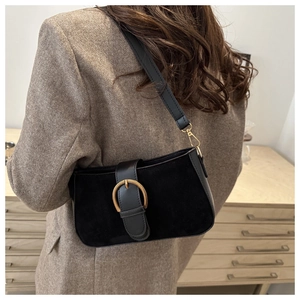 Detail der mattschwarzen Baguette-Tasche mit goldener Schnalle an einem Modell