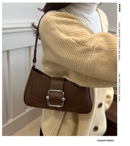 Detail showing deep brown baguette bag with silver metal buckle on a shoulder strap