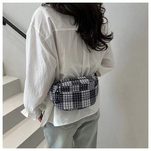 Detail of plaid waist bag featuring black and white check pattern with triangle zipper pull