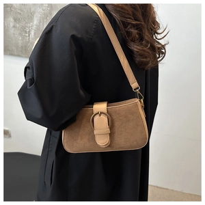 Detail einer braunen Wildleder-Schultertasche mit einer großen dekorativen Metallschnalle